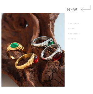 Detail view of gold and silver Egyptian rings with red and green gems on wood