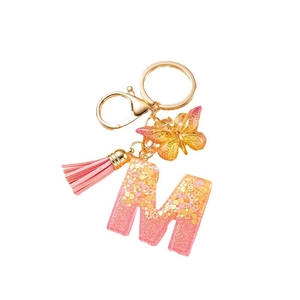 Custom gold butterfly and pink tassel keychain with glitter letter M on white background