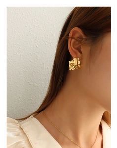 Primo piano di modella con orecchini dorati dalla texture stropicciata irregolare in oro 18K