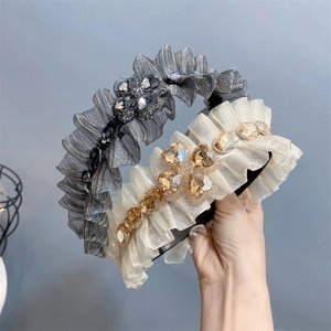 Detail view of ruffle fabric headbands in grey and beige with crystal rhinestone accents