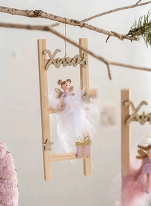 Close-up of pink angel doll on wooden ladder with golden Xmas lettering ornament
