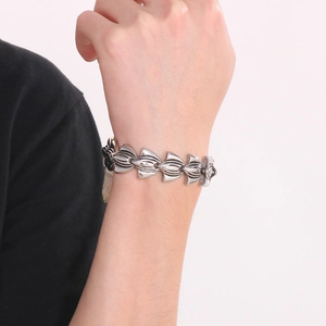 Close-up of gothic silver fishtail anchor bracelet with ornate carved leaf links on wrist