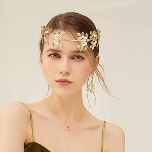 Close-up of golden leaf bridal headband set with pearls worn by a model in soft lighting