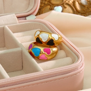Detail of 18k gold heart rings with white and multicolor enamel on a velvet box