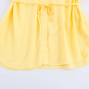 Detailed close-up of yellow shirt hem featuring white buttons and adjustable waist drawstring