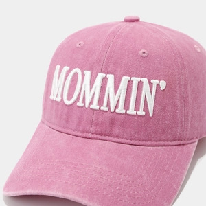 Macro view of white MOMMIN embroidery on washed cotton fabric of the pink baseball cap