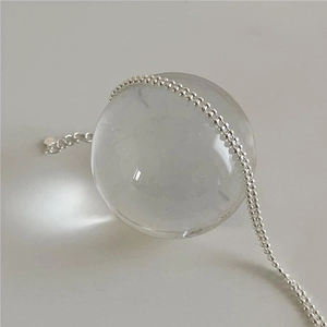 Macro shot of minimalist S925 sterling silver ball chain draped over a crystal ball