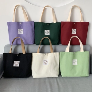 Detail of colorful canvas tote bags with cute dog patches and sturdy metal snap buttons