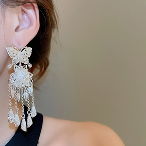 Detail of silver filigree butterfly earrings with long tassels on a model