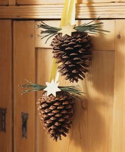 Natural pine cone hanging ornament with wooden stars and pine needles on rustic wood