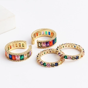 Close-up of four adjustable gold rings with colorful cubic zirconia in a set display