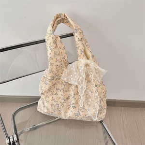 Detailed texture of floral canvas tote bag featuring a decorative white lace bow accent