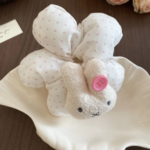 Detailed close-up of a white polka dot hair scrunchie featuring a plush bunny decoration