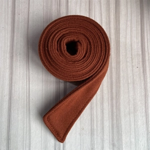 Detailed close-up of reddish-brown woolen coat belt with high-quality stitching