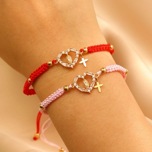 Detail of pink and red braided bracelets with cross and religious charms on wrist