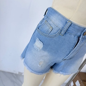 Close-up of light blue distressed denim shorts with frayed hems and ripped texture details