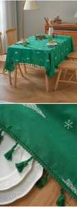 Macro detail of green Christmas tablecloth showing festive reindeer embroidery and fringe edges