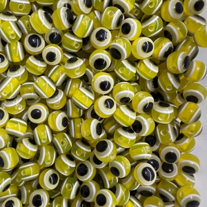 Detailed close-up of bulk yellow evil eye beads for handmade jewelry DIY necklaces