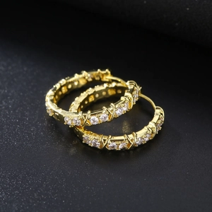 Macro shot of gold-plated hoop earrings featuring micro-pave cubic zirconia and X-shaped detail