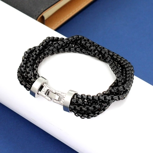 Detail of multi-layer black metal chain bracelet with silver clasp on a blue background