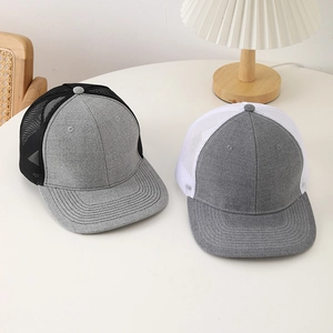 Gros plan de casquettes de camionneur en mesh gris, noir et blanc sur un bureau