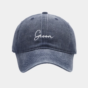 Detail of navy washed cotton baseball cap featuring white Groom embroidery on the front