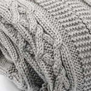 Macro shot of gray chunky knit leg warmers showing detailed cable pattern and wool texture