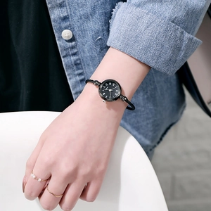 Close-up of minimalist black dial quartz watch with Roman numerals on female wrist