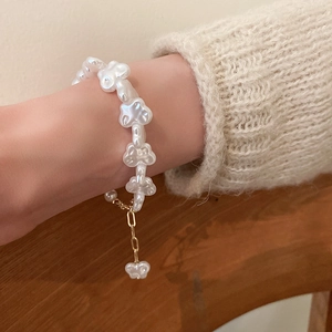 Detail of irregular pearl flower bracelet with golden toggle clasp on wool sweater