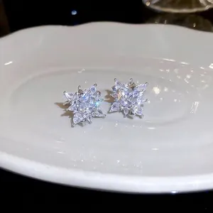 Sparkling star zircon ear clips in silver metal displayed on a white ceramic tray