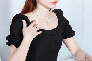 Silver key pendant necklace with shell inlay worn by model on a black outfit