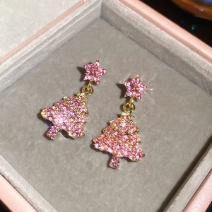 Vue macro de boucles d'oreilles sapin de Noël en strass rose avec pompon étoile