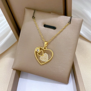 Detail of gold titanium heart necklace with hollow design and sparkling crystal inlay