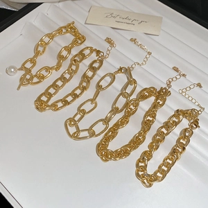 Close-up of gold chunky chain bracelets set with OT clasp and pearl charm detail
