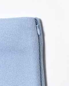 Détail de maille fine bleu clair montrant la fermeture éclair invisible et couture