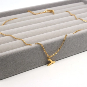 Detail of a gold-plated letter Y pendant necklace on a premium grey velvet display tray