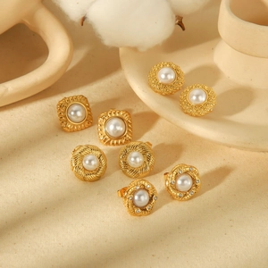 Set of golden stainless steel geometric earrings with elegant white pearls on beige fabric