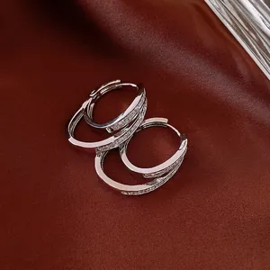 Double layered silver hoop earrings with cubic zirconia on a red silk background