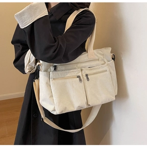 Detail view of beige corduroy crossbody bag featuring multiple zipper pocket storage