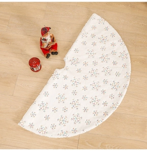 Close-up of plush white Christmas tree skirt featuring colorful sequin snowflake patterns