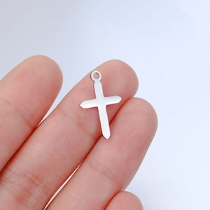 Polished silver stainless steel cross pendant shown in hand for size reference