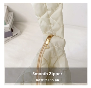 Close-up of white quilted puffer bag featuring a smooth gold metal zipper and fine stitching