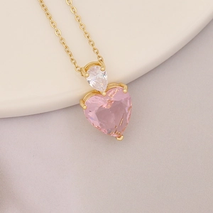 Detail of 18K gold-plated necklace with pink heart pendant and teardrop zircon on ceramic