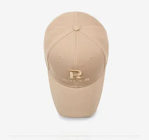 Detailed close-up of R RELAXATION gold embroidery on a beige cotton baseball cap