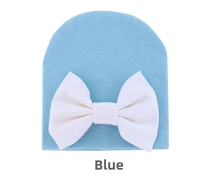 Close-up of light blue knit baby beanie with a large white fabric bow detail