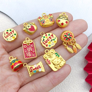 Golden Maneki Neko and Lucky charm pendants with colorful enamel on a person's hand