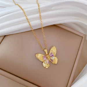 Detailed macro view of gold butterfly pendant with purple stones in luxury gift box
