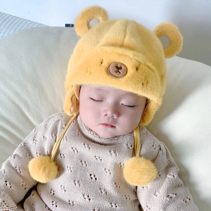 Dettaglio del cappello in peluche a orsetto giallo con orecchie e trama del maglione beige