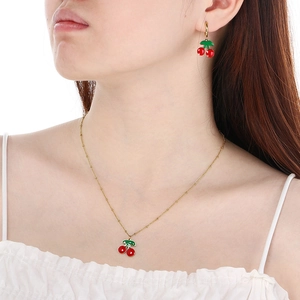 Parure de bijoux cerise en acier doré avec collier et boucles d'oreilles sur un modèle
