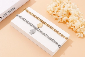 Dettaglio di braccialetti Mano di Fatima in oro e argento su pietre geometriche bianche